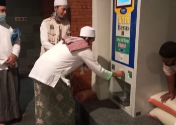 Pengurus Masjid Al Khalid Kediri mengoperasikan ATM Beras untuk membantu warga terdampak corona.