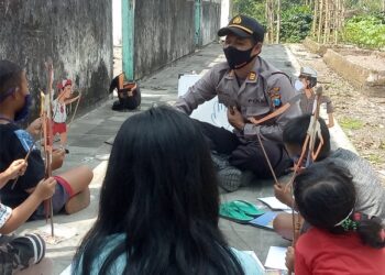 Bowo Wicaksono, anggota Polres Kediri saat memainkan wayang kardus bersama anak-anak. Foto: Bacaini