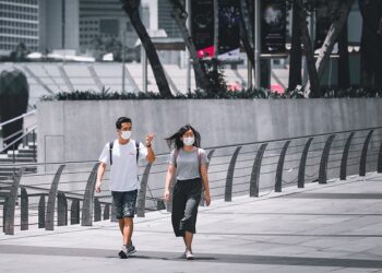 Dua pekerja di Singapura berjalan mengenakan masker. Foto: Unsplash