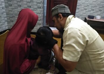 Ulu Hadi saat membacakan ayat Al Quran di telinga anak kecil. Foto: Bacaini