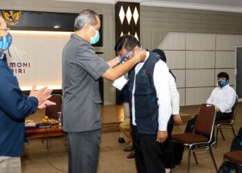 Setda Kota Kediri Budwi Sunu mengalungkan ID petugas survei. Foto: Pemkot