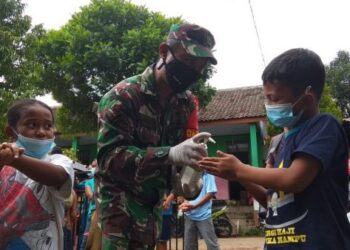 Anggota TNI memberikan handsanitizer kepada salah satu pengungsi