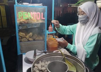 Dewi menemani ayahnya berjualan pentol di Jalan Veteran Kediri. Foto: Bacaini/Novira Kharisma