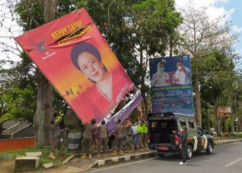 Anggota Satpol PP Kota Batu menurunkan baliho Puan yang dirusak. Foto: Bacaini/A. Ulul