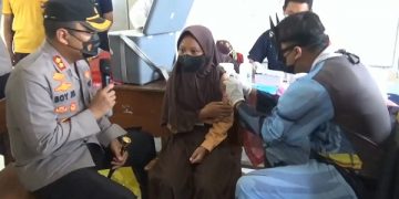 Vaksinator berkostum Batman memberikan suntikan vaksinasi untuk anak SD di Nganjuk. Foto:Bacaini