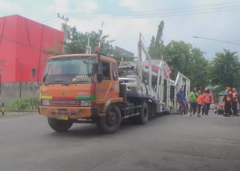 Truk pengagkut mobil tersangkut di perlintasan kereta api. Foto:Bacaini/AK Jatmiko