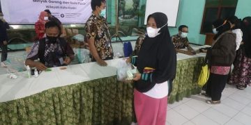 Salah satu ibu-ibu membeli minyak goreng dan gula pada operasi pasar. Foto: Ist