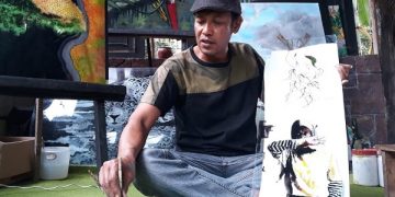 Budianto menunjukan hasil karya seni lukis kaca menggunakan media limbah kaca bus. Foto: Bacaini/Setiawan