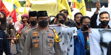 Kapolres Nganjuk, AKBP Boy Jeckson terlihat memakan peci saat mengawal mahasiswa peserta aksi. Foto: Ist