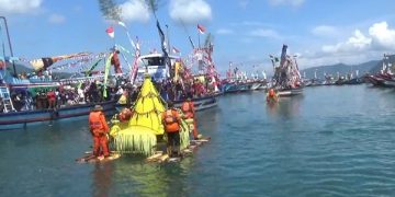 Para nelayan dan masyarakat melarung tumpeng raksasa menuju tengah laut. Foto: Bacaini/Aby