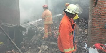 Petugas Damkar tengah memadamkan api yang membakar rumah warga. Foto: Bacaini/Novira
