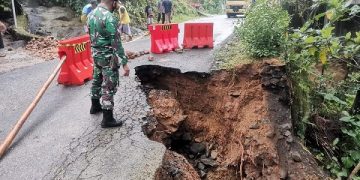 Kondisi jalan yang ambles dijaga petugas. Foto: Ist