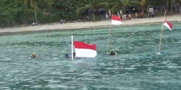 Proses pengibaran bendera merah putih di bawah laut Pantai Mutiara. Foto: Bacaini/Aby