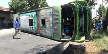 Bus PO Madjoe yang terguling di jalan raya Begadung, Kabupaten Nganjuk. Foto: Bacaini/Asep Bahar