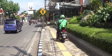 Seorang pengemudi ojek online tengah menunggu orderan penumpang. Foto: Bacaini/AK.Jatmiko