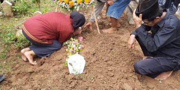 Cindy Novianti, istri Briptu Fajar Yoyok Pujiono mencium nisan makam suaminya. Foto; Bacaini/Aby
