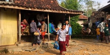Salah seorang anak menenteng kantong plastik berisi buah hasil rebutan. Foto: Bacaini/Rusdi