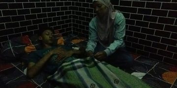Nur Hafiz Al Zaki terbaring lemas ditemani ibunya. Foto: Bacaini