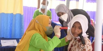 Ferry Silviana Abu Bakar meninjau pemeriksaan telinga salah satu siswi SD. Foto: Ist