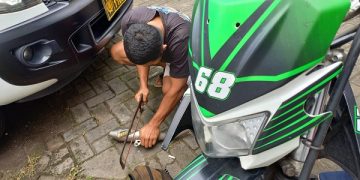 Salah seorang pemilik sepeda motor yang terjaring razia sedang menggergaji knalpot brong. Foto: Bacaini/Setiawan