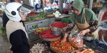 Siti Fatimah, salah satu pedagang di Pasar Basah Trenggalek tengah melayani pembeli cabai. Foto: Bacaini/Aby