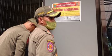 Petugas Satpol PP menempel stiker segel tanda penutupan sementara. Foto: Bacaini/A.Ulul