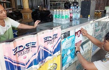 Petugas memasang stiker sosialisasi di toko. Foto:Bacaini.id/Setiawan