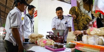 Petugas Disperdagin saat memeriksa timbangan salah satu pedagang di Pasar Bandar. Foto: Ist
