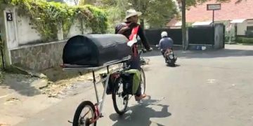 Midun memulai perjalanan ke Jakarta dengan sepeda pancal dan keranda jenazah di belakangnya. Foto: Ist