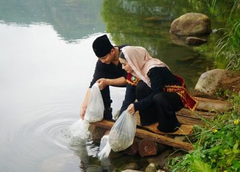 Bupati Arifin bersama Novita Hardini menebar benih ikan tawes. Foto: Ist