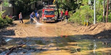 Petugas membersihkan material longsor dan banjir lumpur di Jalan Raya Bandung–Prigi, Kecamatan Watulimo, Trenggalek