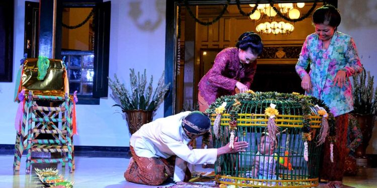 Prosesi ritual Tedak Siten dengan bayi berjalan di atas jadah tujuh warna dalam tradisi Jawa