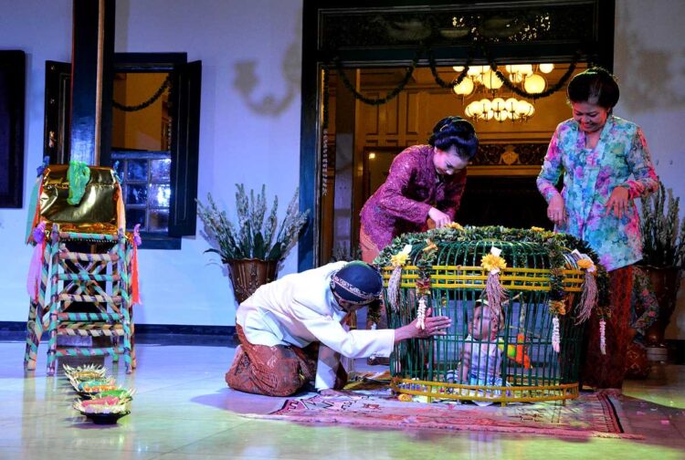 Prosesi ritual Tedak Siten dengan bayi berjalan di atas jadah tujuh warna dalam tradisi Jawa