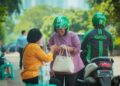 Driver ojek online melintas dengan atribut Grab dan Gojek setelah aturan baru Perpres Ojol 2026 tentang pemotongan komisi aplikasi maksimal 8 persen