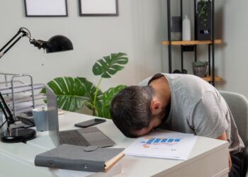 Pria kantoran terlihat lelah dan mengantuk saat bekerja di sore hari karena afternoon slump