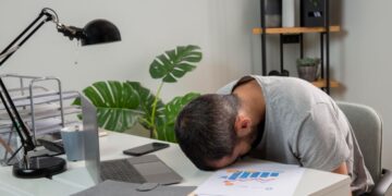 Pria kantoran terlihat lelah dan mengantuk saat bekerja di sore hari karena afternoon slump