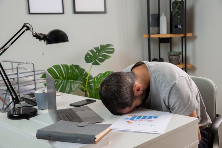 Pria kantoran terlihat lelah dan mengantuk saat bekerja di sore hari karena afternoon slump