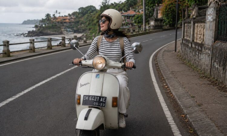 Perempuan melakukan solo riding menggunakan Vespa